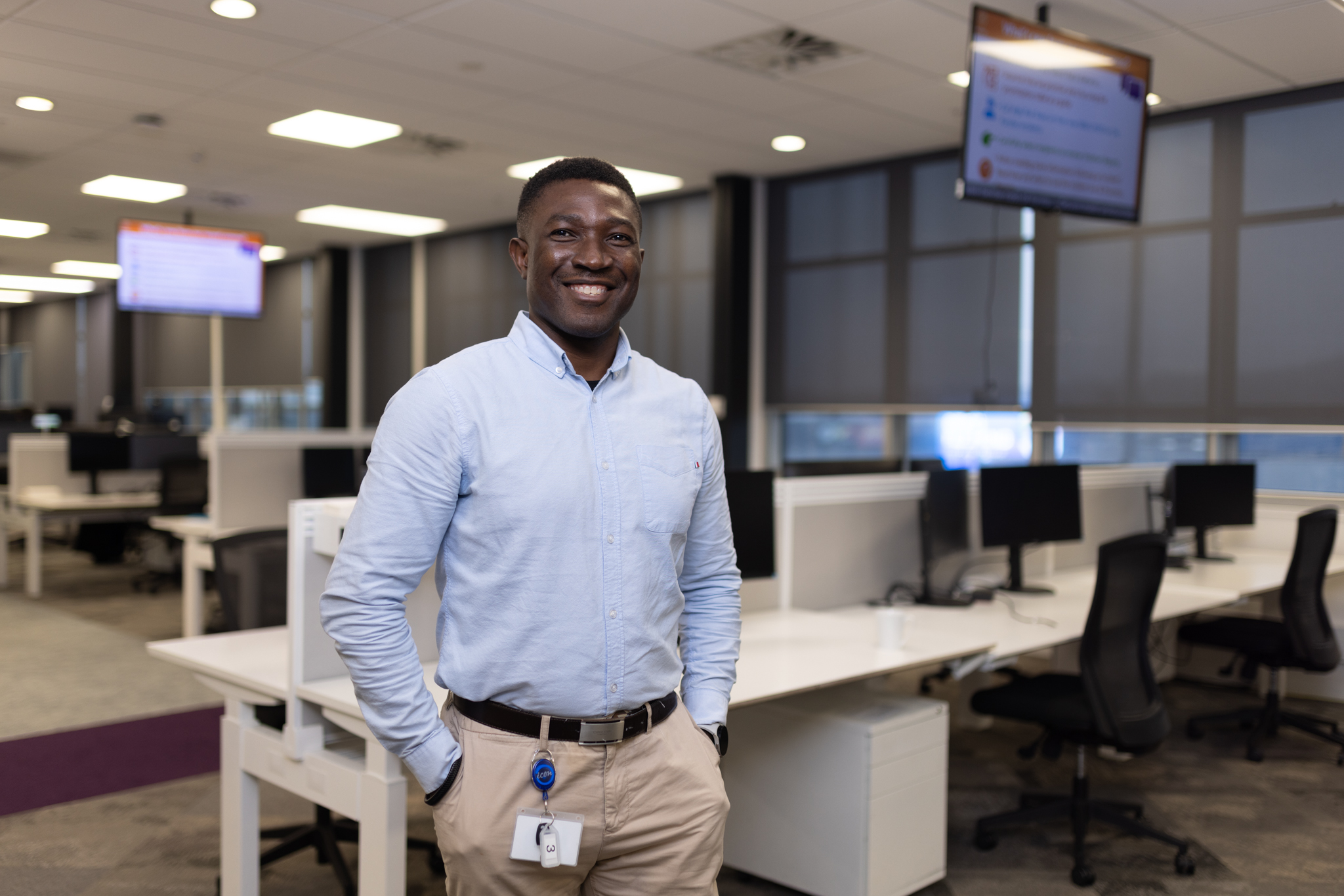 Operations Adviser stands in office for Electronic Monitoring Operations, smiling with rows of desks in the background